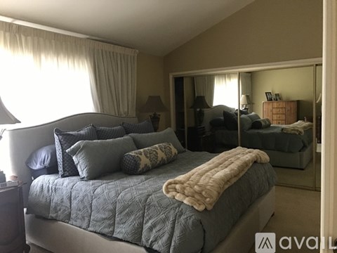 A bedroom with a large bed and a mirror on the wall.