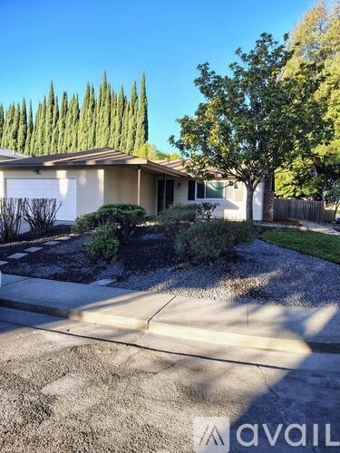 A house with a driveway and a tree in front.