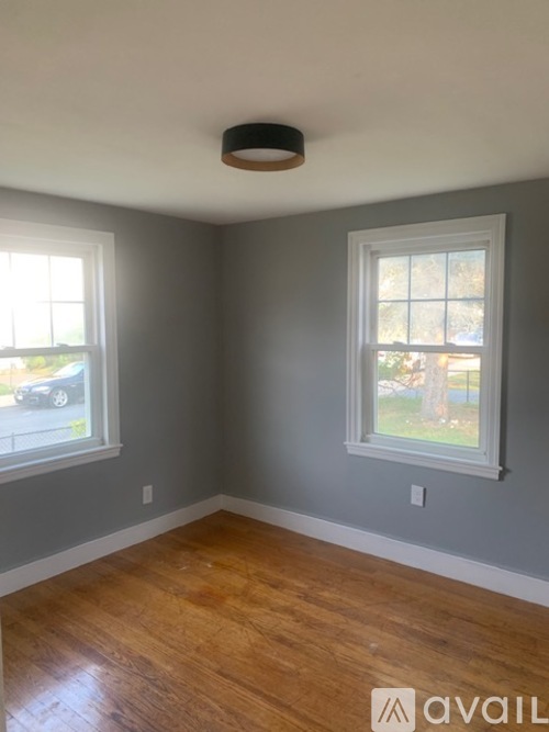 A room with wooden floors and two windows.
