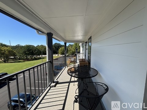 A balcony with a table and chairs overlooking a parking lot.