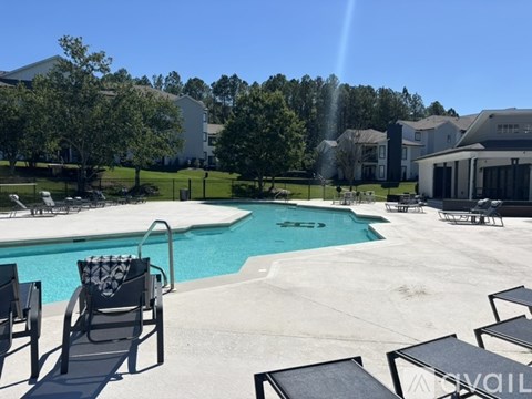 A pool with a slide and lounge chairs is surrounded by houses.