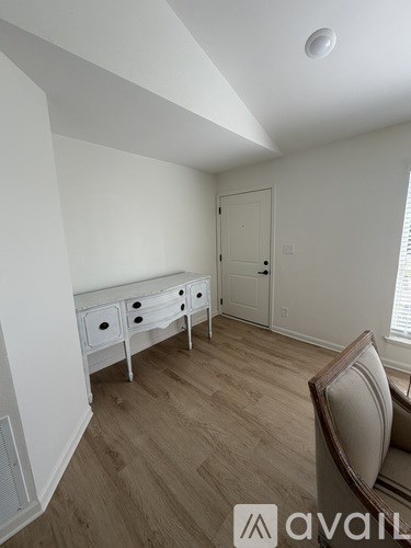 A room with a brown chair and a white dresser with drawers.
