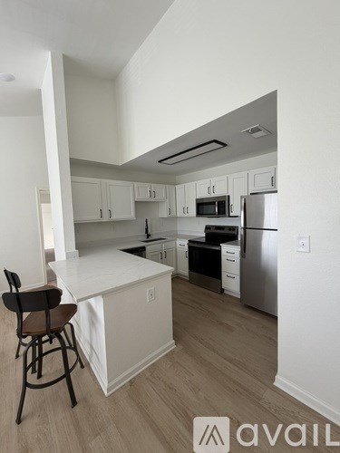 A kitchen with white cabinets and a white island with a bar stool.