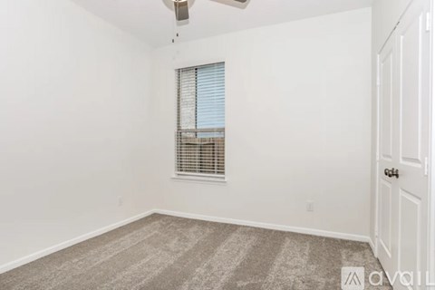 A room with a carpeted floor, a window with blinds, and a ceiling fan.