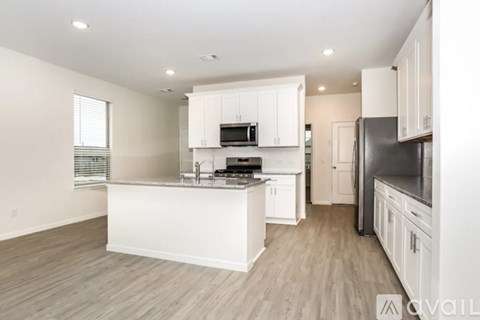 A kitchen with white cabinets and a wooden floor.