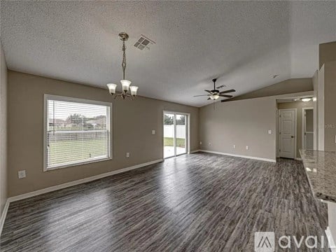 A spacious room with wood flooring and a ceiling fan.