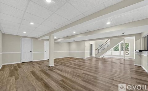 A spacious room with wooden flooring and white walls.