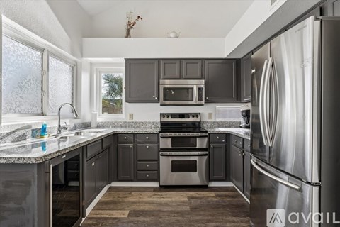 A modern kitchen with dark grey cabinets and stainless steel appliances.