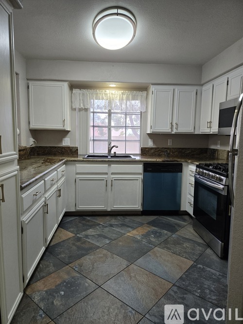 A kitchen with a checkered floor and white cabinets.
