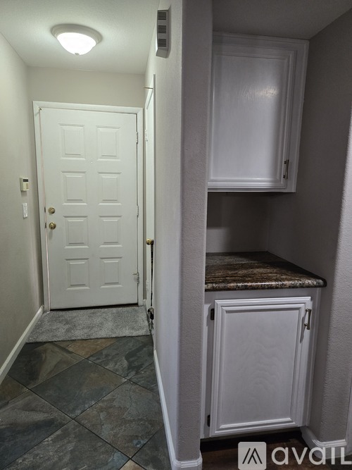 A white door is open to a small kitchen.