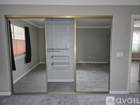 A bedroom with a large mirror and a walk-in closet.