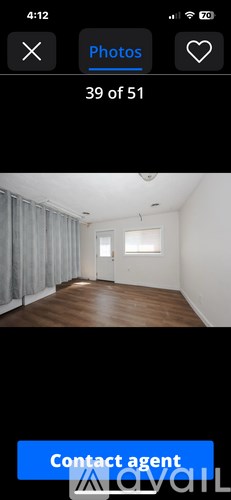 A room with wooden flooring and a window with white curtains.