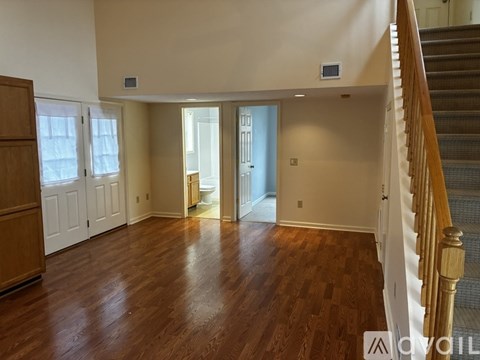 A room with wooden floors and a staircase leading to another room.