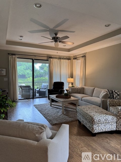 A living room with a couch, chair, and a fan.