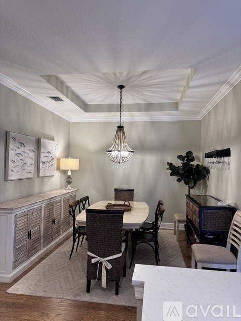 A dining room with a table set for four and a chandelier hanging from the ceiling.