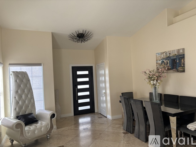 A living room with a white chair and a painting on the wall.