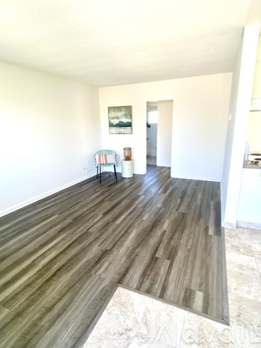 A room with a wooden floor and a painting on the wall.