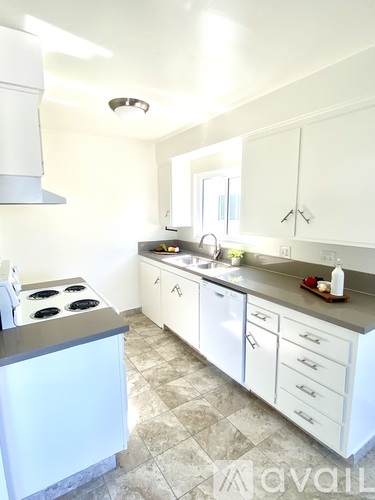 A kitchen with white cabinets and a tiled floor.