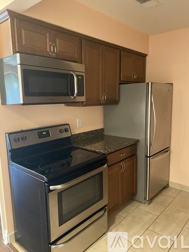 A kitchen with a black stove top oven, a black microwave, and a silver refrigerator.
