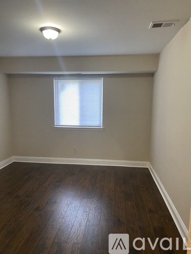 A room with wooden flooring and a window with blinds.