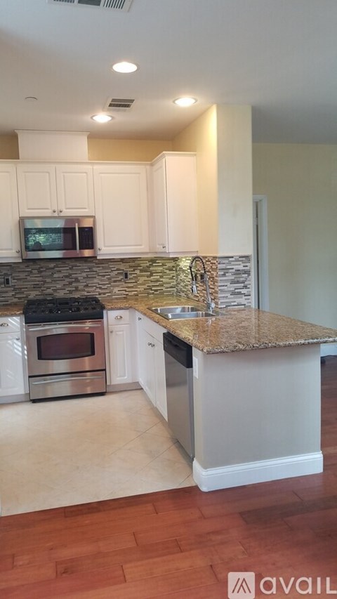 A kitchen with a granite countertop and stainless steel appliances.