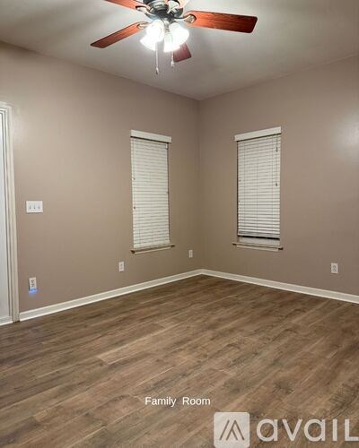 A family room with a ceiling fan and wood flooring.