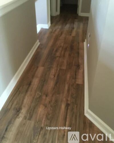 A hallway with wood flooring and white walls.