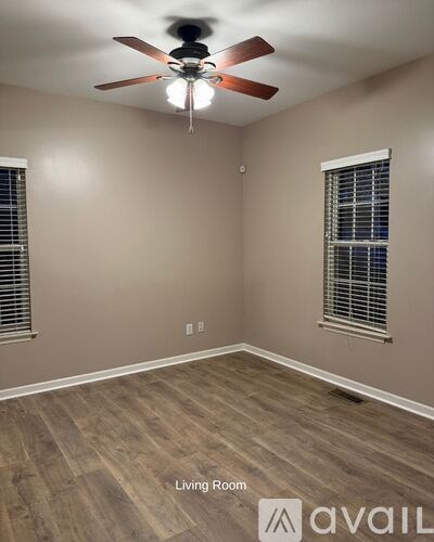 A living room with a ceiling fan and wood flooring.