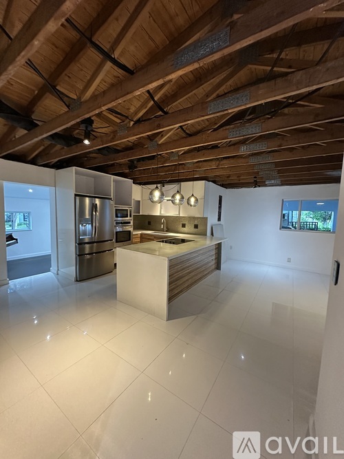 A spacious kitchen with wooden ceiling and white tiled floor.