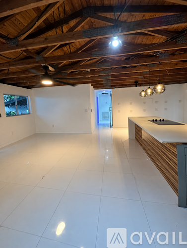 A spacious room with a kitchen area and a ceiling fan.