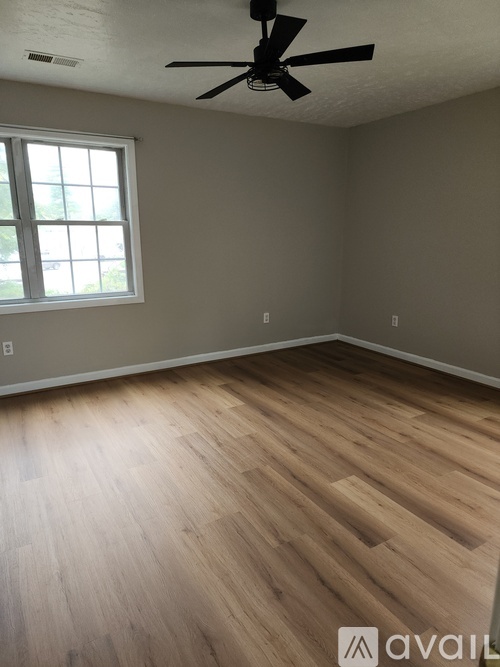 A room with a ceiling fan and wooden flooring.