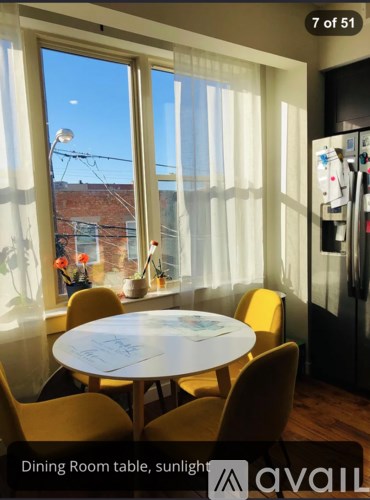 A dining room table with chairs and a fridge in the corner.