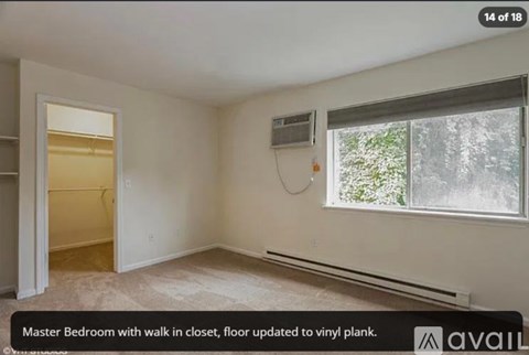 A bedroom with a walk-in closet and a window with a view of trees.