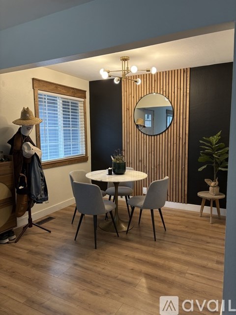 A dining room with a round mirror and a wooden floor.