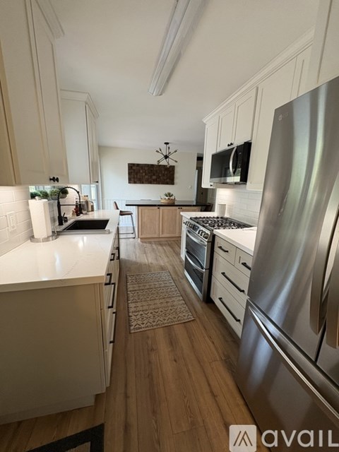A modern kitchen with stainless steel appliances and wooden floors.