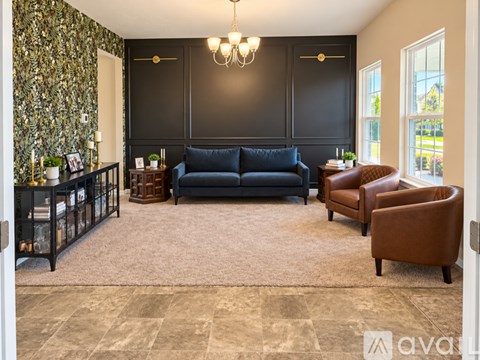 A living room with a black couch and a brown armchair.