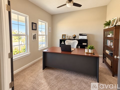 A room with a desk, a fan, and a window.