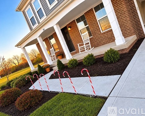 A house with a white porch and a red and white striped caution tape in front of it.