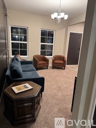 A living room with a blue couch, two chairs, and a coffee table.