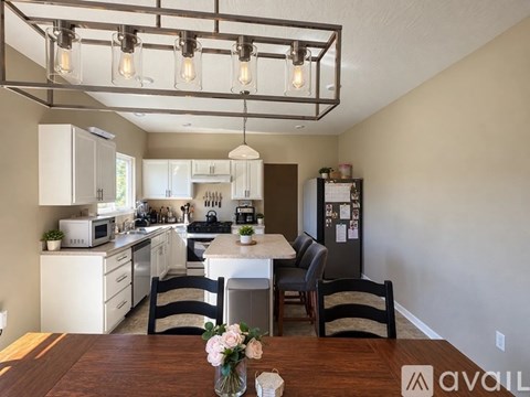 A kitchen with a table and chairs in the foreground and a fridge in the background.