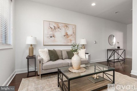 A living room with a couch, two lamps, a painting, and a mirror.