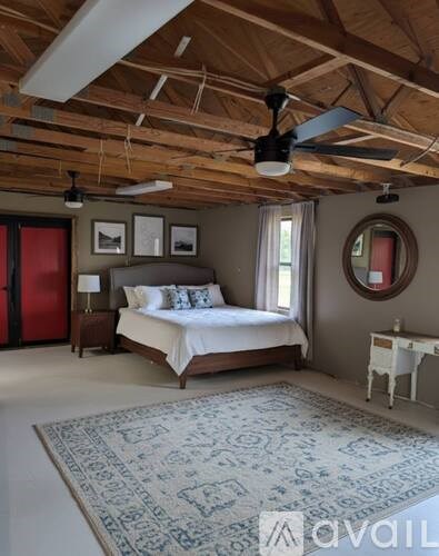 A bedroom with a bed, a fan, and a rug.