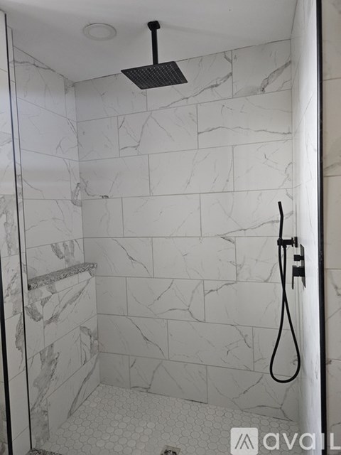 A shower with a black shower head and a black hose.