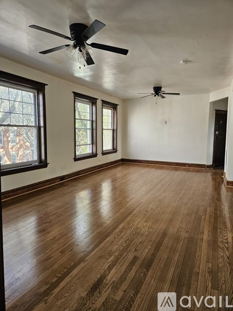 A room with wooden floors and two ceiling fans.