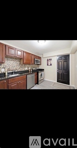 A kitchen with brown cabinets and a black refrigerator.