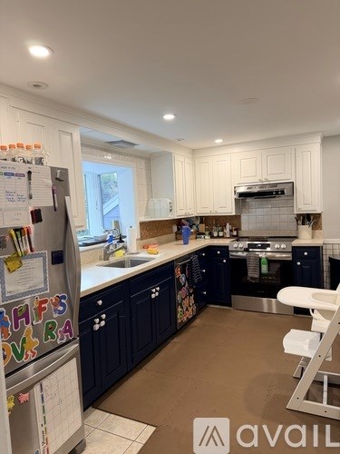 A kitchen with dark blue cabinets and a white fridge.