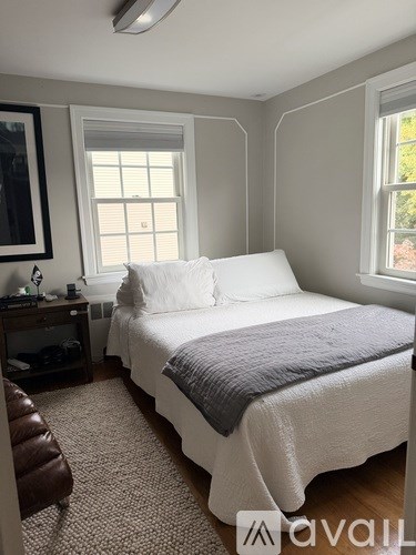 A bedroom with a bed, a chair, and a window.