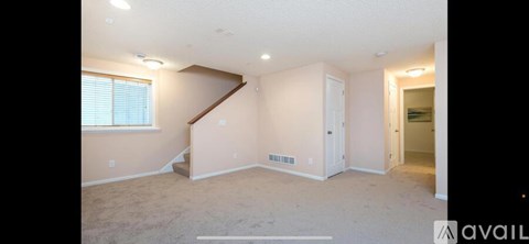A spacious room with a staircase leading to the upper level.