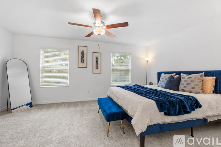 A bedroom with a bed, a fan, and a mirror.