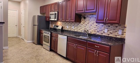 A kitchen with brown cabinets and a black countertop.